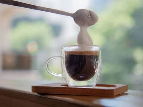 Glas mit Espresso und Milchschaum vor verschwommenem Hintergrund