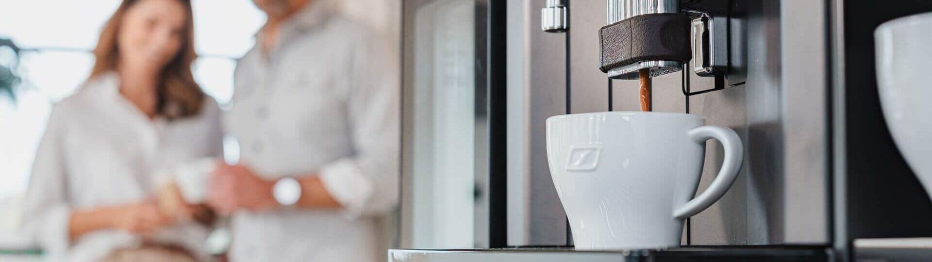 Frischer Kaffee läuft aus Kaffeevollautomat in eine weiße Tasse