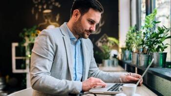 Ein Mann sitzt an einem Tisch und arbeitet an einem Laptop