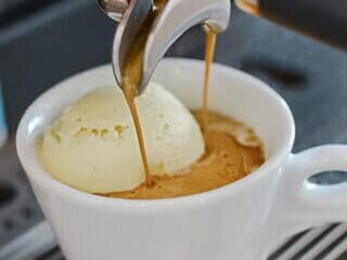 Espresso wird über Vanilleeis in Tasse als Affogato gegossen