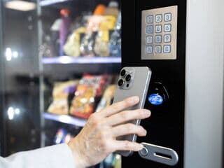 Person bezahlt am Verkaufsautomaten kontaktlos mit Smartphone per NFC-Technologie