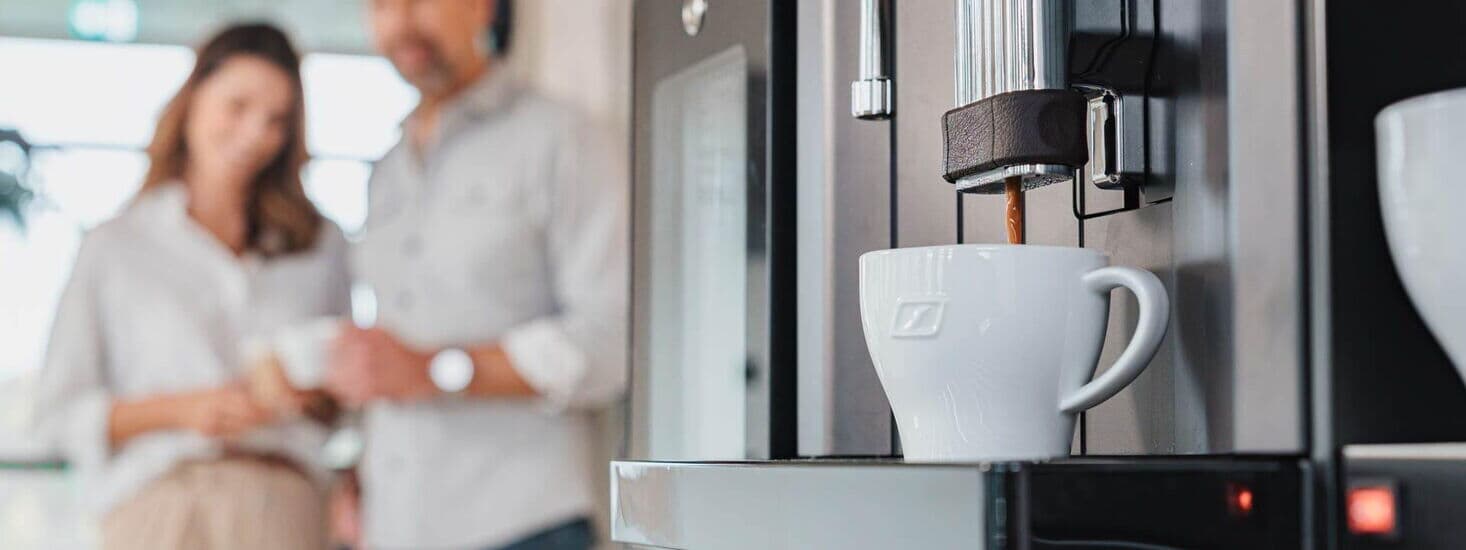 Fresh coffee flows from machine into a white cup