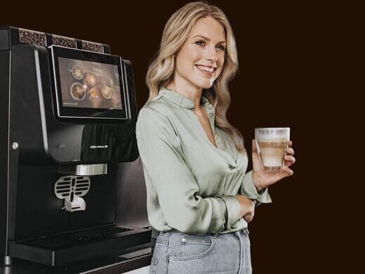 Frau freut sich über Cappuccino aus dem Vollautomaten