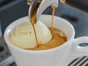 Espresso wird über Vanilleeis in Tasse als Affogato gegossen